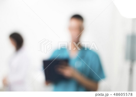 Men in a cyan colored dental coat taking notes 48605578
