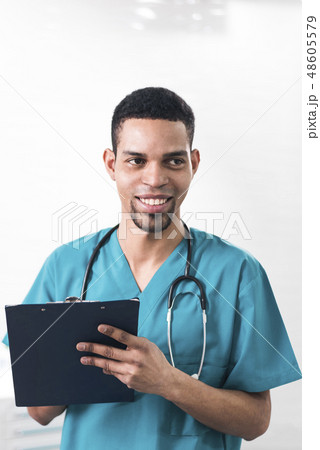 Men in a cyan colored dental coat taking notes 48605579