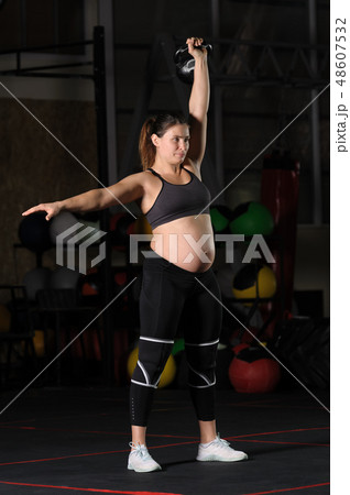 Pregnant female athlete doing hang kettlebell clean and press Pregnant female athlete doing hang kettlebell clean and press 48607532