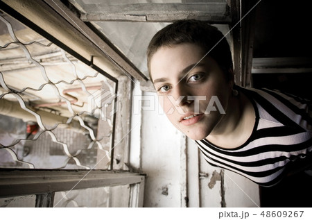 A young girl with a short hair stays by the window A young girl with a short hair stays by the window 48609267