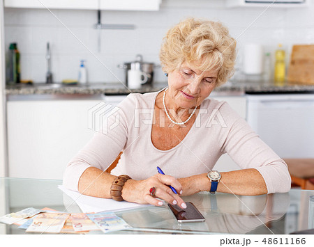 Woman counting her expenses using smartphone Woman counting her expenses using smartphone 48611166