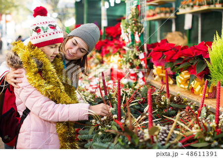 Girl with mother choosing floral decoration Girl with mother choosing floral decoration 48611391