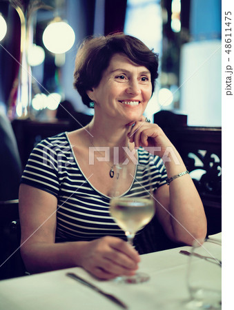 Elderly woman has rest at restaurant with wineglass Elderly woman has rest at restaurant with wineglass 48611475