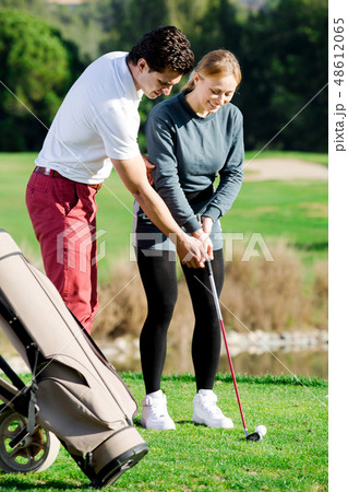 Golf trainer teaches a woman game 48612065