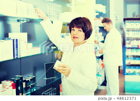 Pharmacist and pharmacy technician posing in drugstore Pharmacist and pharmacy technician posing in drugstore 48612371