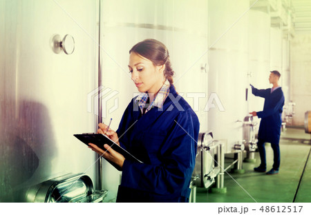 Female winery employee in uniform taking off data 48612517