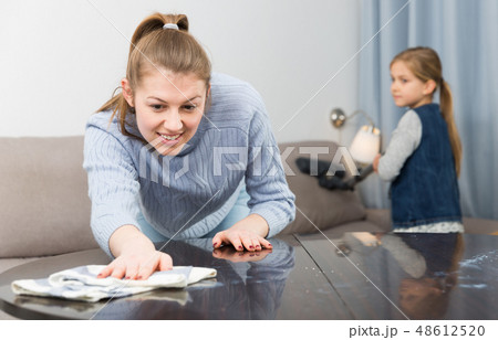 Woman with vacuum cleaner and daughter with rag Woman with vacuum cleaner and daughter with rag 48612520