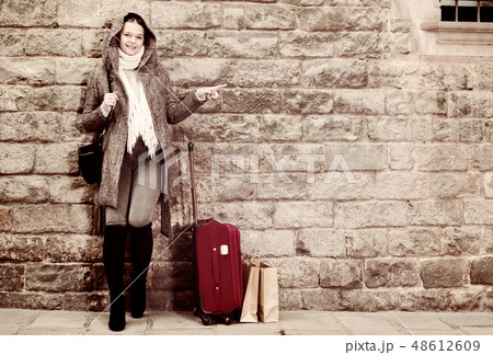 girl in hood and coat with baggage near wall girl in hood and coat with baggage near wall 48612609