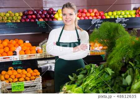 Young female in apron selling greens and letuce on the market 48612635