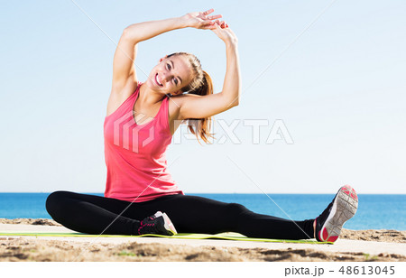 Woman doing yoga at beach Woman doing yoga at beach 48613045