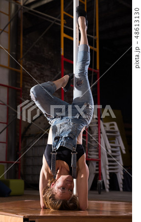 Young woman in ripped jeans performing pole dance Young woman in ripped jeans performing pole dance 48613130