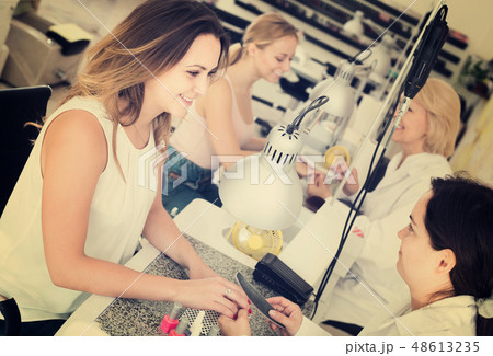 Female clients doing nails in nail salon in afternoon Female clients doing nails in nail salon in afternoon 48613235