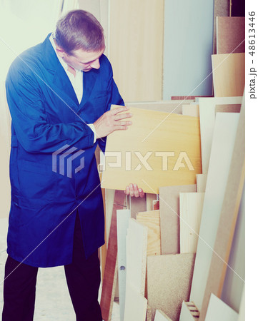 portrait of man in uniform choosing compressed densified wood in picture framing atelier 48613446