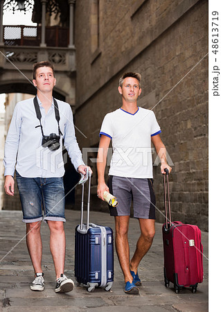 Two young men in shorts with baggage walking in city 48613719