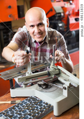 Workman making mailbox plate in workshop. 48613839