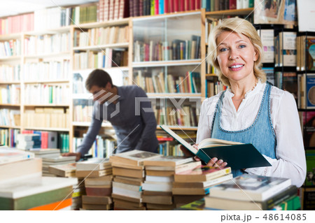 Cheerful mature female holding open book Cheerful mature female holding open book 48614085