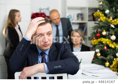 Business team tensely solving problems in office with offended man foreground Business team tensely solving problems in office with offended man foreground 48614167