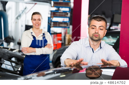 Male client inspecting painting quality of vehicle 48614702