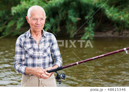 Mature man angling at riverside Mature man angling at riverside 48615346