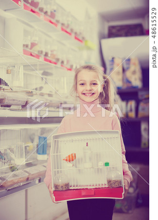 girl customer happy about buying cage with canary bird in pet shop 48615529