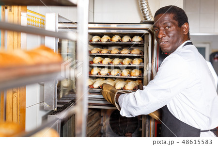 Baker taking out bread from oven 48615583