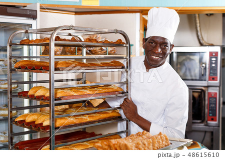 Baker pushing trolley with baked baguettes 48615610
