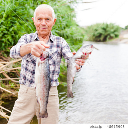 Fisherman posing with catch at riverside 48615903