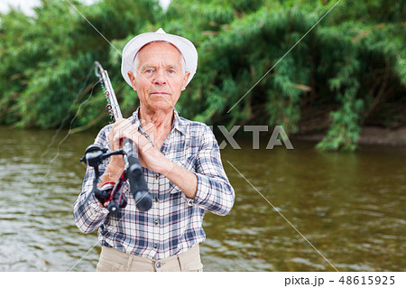 Mature fisherman with rod at riverside 48615925