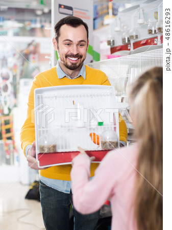 Smiling male seller offering cage with canary bird Smiling male seller offering cage with canary bird 48616293