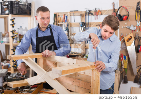 father and son repairing wood bench at garage father and son repairing wood bench at garage 48616558