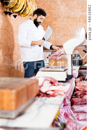 Male shop assistant carving meat Male shop assistant carving meat 48616862