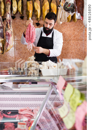 Male seller offering delicious sausages Male seller offering delicious sausages 48616890