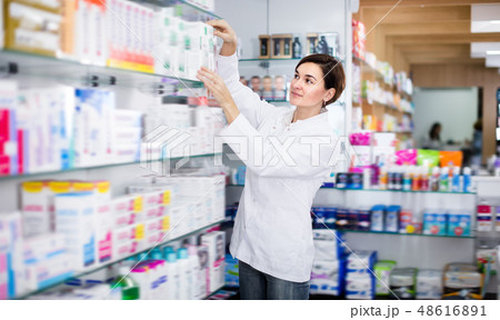 Pretty female pharmacist offering products Pretty female pharmacist offering products 48616891