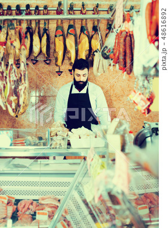 Shop assistant arranging meat to sell in butcher’s shop 48616892