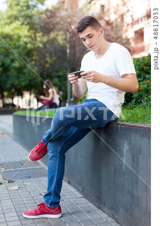 Guy texting on his smartphone in park 48617053