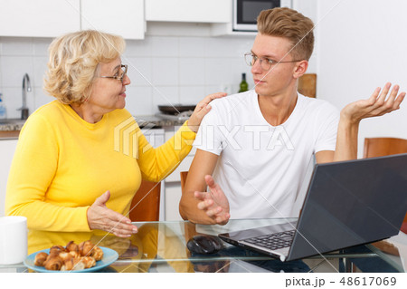 Woman scolding her upset adult son Woman scolding her upset adult son 48617069