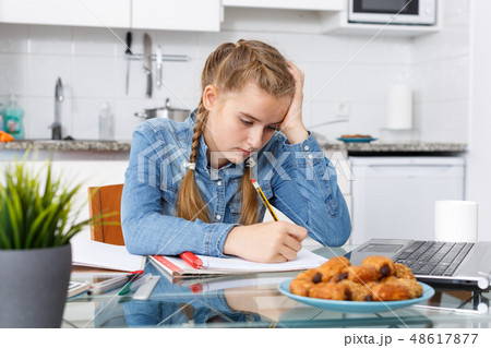 Girl doing her homework with laptop Girl doing her homework with laptop 48617877
