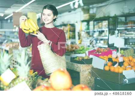 Portrait of brunette girl buying ripe bananas in supermarket 48618160