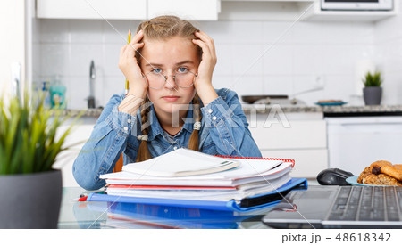 Tired girl sitting among notebooks Tired girl sitting among notebooks 48618342