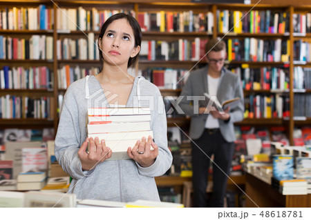 Glad student standing with pile of books Glad student standing with pile of books 48618781