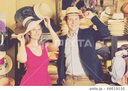 positive young female and man choosing hats in the store 48619130