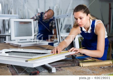 Workwoman is checking dimensions of finished plastic window usin Workwoman is checking dimensions of finished plastic window usin 48619601