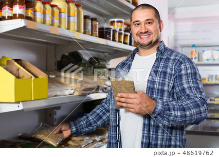 Male customer choosing nuts and grain in average food shop 48619762