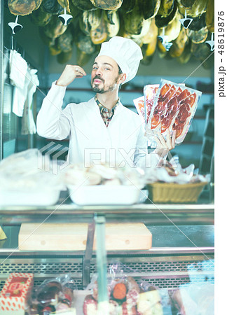 friendly man seller showing sliced bacon in shop friendly man seller showing sliced bacon in shop 48619876