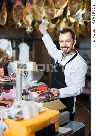 male seller weighing piece of meat in butcher’s shop 48619918