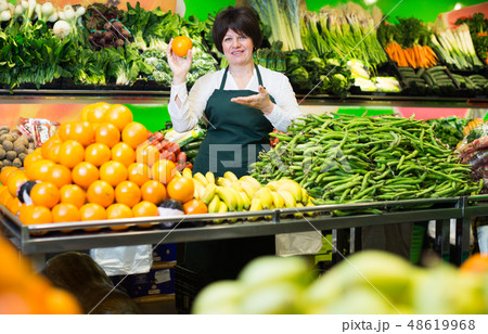 Mature woman offering fresh fruits and vegetables Mature woman offering fresh fruits and vegetables 48619968