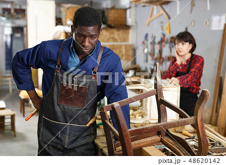 Craftsman restoring old chair in studio 48620142