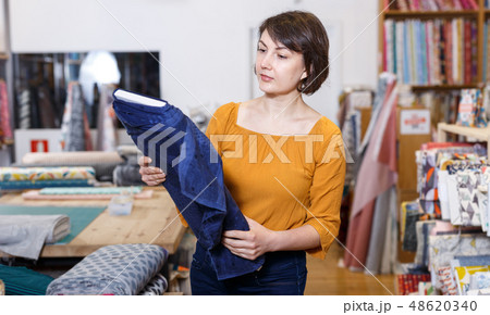 Brunette choosing fabric in store Brunette choosing fabric in store 48620340