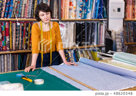 Woman seller of tissue store near cutting table 48620348
