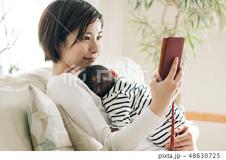 赤ちゃんを抱きながらスマホを見る母親 育児 子育て 赤ちゃんを抱きながらスマホを見る母親 育児 子育て 48630725